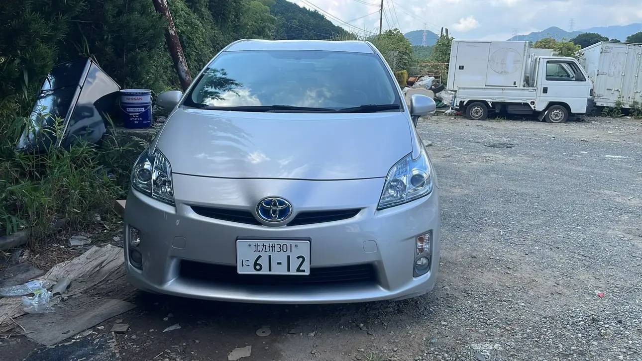 屋外ヤードに停車するシルバーのトヨタ プリウス正面