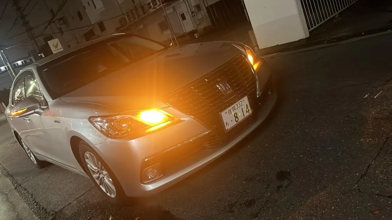 夜間に停車するシルバーのトヨタ クラウン ロイヤルサルーン ハイブリッド