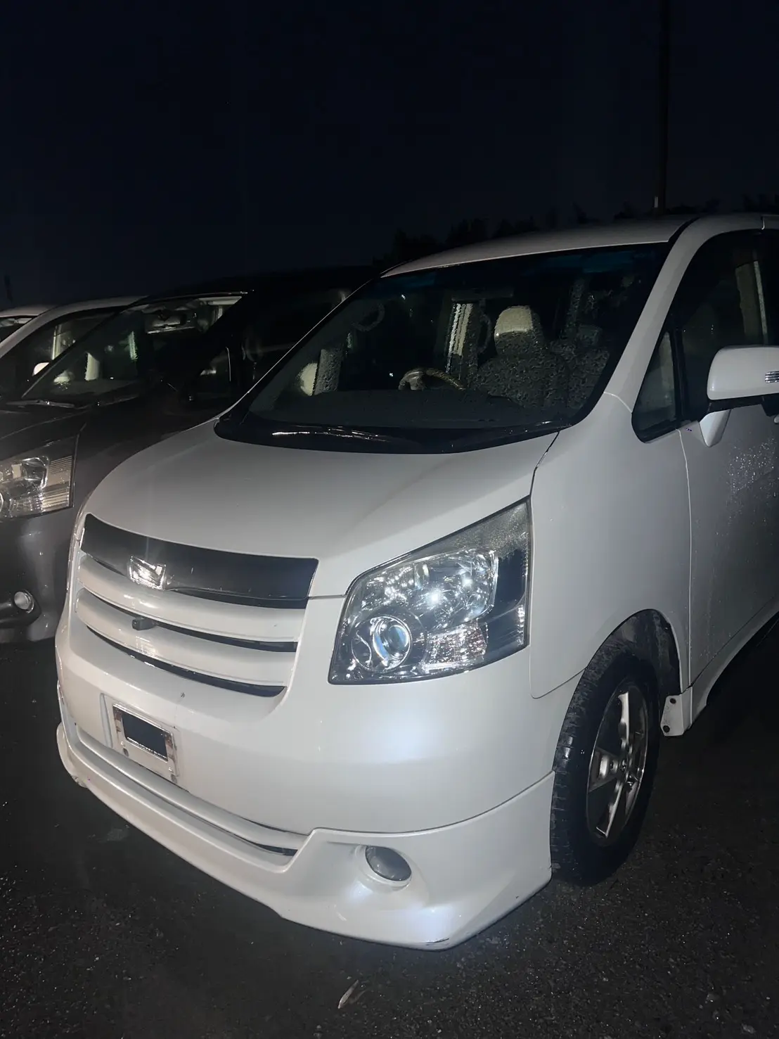 夜間に停車する白いトヨタ ミニバン